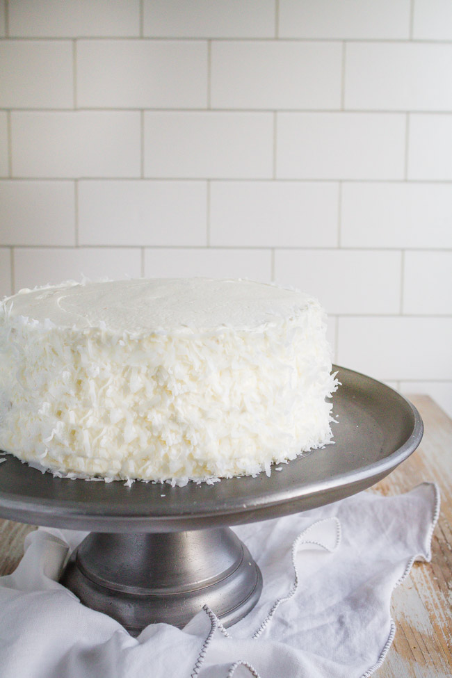 Coconut Cream Cake frosted with coconut butter cream on a silver cake stand